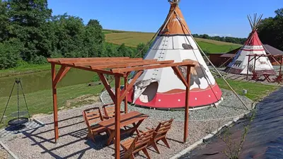 a teepee tent with a wooden table and chairs at Leśny Zakątek Radocza in Radocza