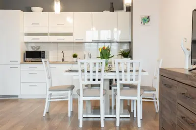a white kitchen with a white table and chairs at Wawrzyńca Apartment with parking in Kraków