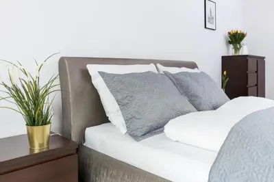 a bed with white and grey pillows on it at Wawrzyńca Apartment with parking in Kraków