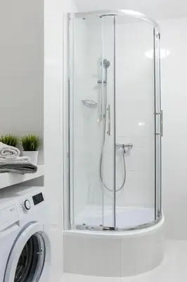 a shower with a glass door next to a washing machine at Wawrzyńca Apartment with parking in Kraków
