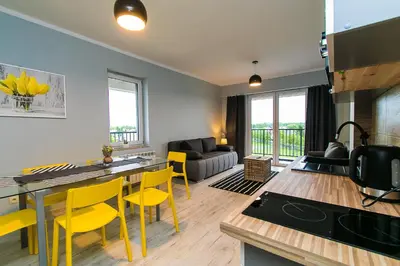 a kitchen and living room with yellow chairs at Apartamenty Niko in Zator