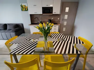 a dining table with yellow chairs and a vase of flowers at Apartamenty Niko in Zator