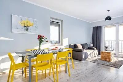 a living room with a dining room table and yellow chairs at Apartamenty Niko in Zator