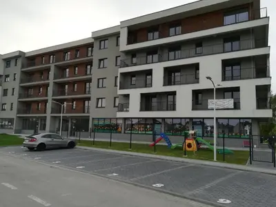 a car parked in front of a building with a playground at Apartamenty Niko in Zator