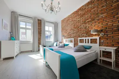 a bedroom with two beds and a brick wall at STAYPOLSKA in Oświęcim