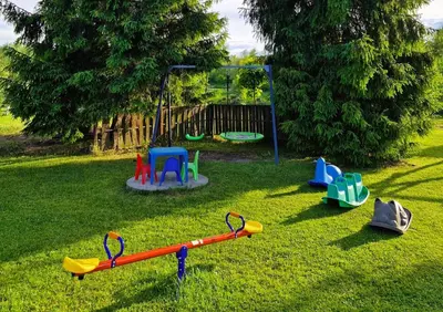 a playground with different colored play equipment in the grass at Bulwary Mszańskie - Domki Całoroczne in Mszana Dolna