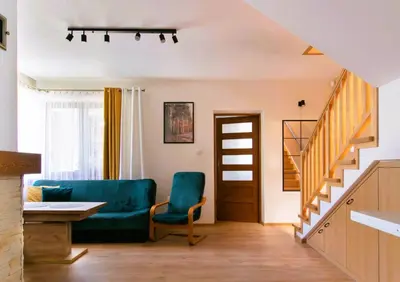 a living room with a blue couch and stairs at Bulwary Mszańskie - Domki Całoroczne in Mszana Dolna