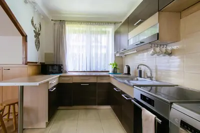 a kitchen with wooden cabinets and a sink and a window at Bulwary Mszańskie - Domki Całoroczne in Mszana Dolna