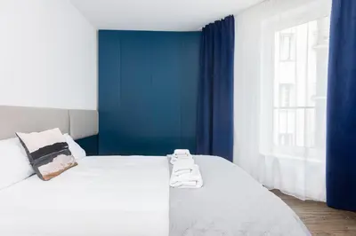 a bedroom with a white bed with blue walls and a window at Apartment Old Town Halicka street by NEARTO in Kraków