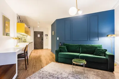 a living room with a green couch and a kitchen at Apartment Old Town Halicka street by NEARTO in Kraków