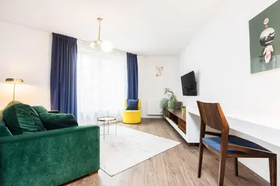 a living room with a green couch and a chair at Apartment Old Town Halicka street by NEARTO in Kraków