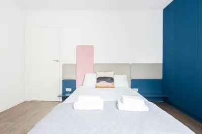 a bedroom with a large white bed with blue walls at Apartment Old Town Halicka street by NEARTO in Kraków