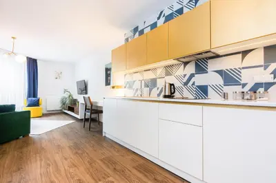 a kitchen with white cabinets and a living room at Apartment Old Town Halicka street by NEARTO in Kraków
