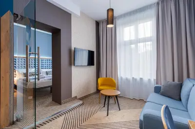 a living room with a blue couch and a yellow chair at Avena Boutique Hotel by Artery Hotels in Kraków