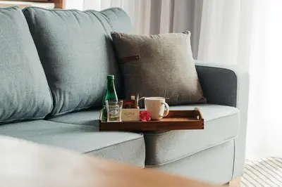 a tray with a bottle and cups on a couch at Avena Boutique Hotel by Artery Hotels in Kraków