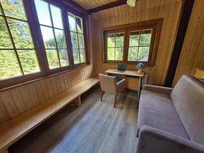 a room with a couch and a desk and windows at Rodzinny Dom Wypoczynkowy Grzechynia Carchla in Grzechynia