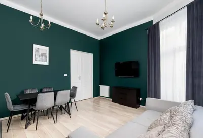 a living room with green walls and a table and chairs at Miodowa Boutique Residence in Kraków