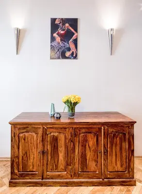 a wooden cabinet with a vase of flowers on top at Apartment Sare 11 in Kraków