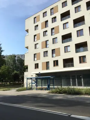 a building with a bus stop next to a street at SHOQ STUDIO nice apartment with private parking in Kraków