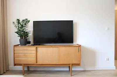 a flat screen tv sitting on top of a wooden dresser at SHOQ STUDIO nice apartment with private parking in Kraków