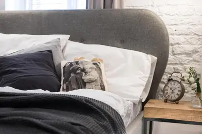 a bed with black and white pillows and a clock at Bożego Ciała by Homeprime in Kraków