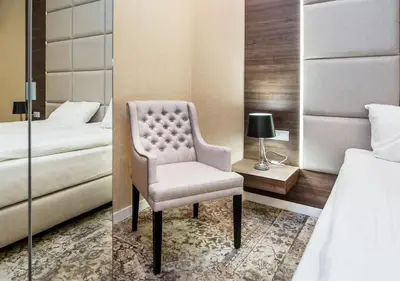 a bedroom with a chair next to a bed at Aparthotel Rakowicka Residence in Kraków