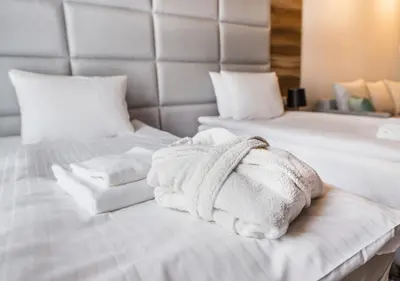 a white bed with towels on top of it at Aparthotel Rakowicka Residence in Kraków