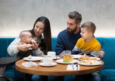a family sitting at a table with a baby at Aparthotel Rakowicka Residence in Kraków