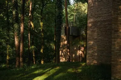 a brick building next to a group of trees at Forest Hotel in Kraków