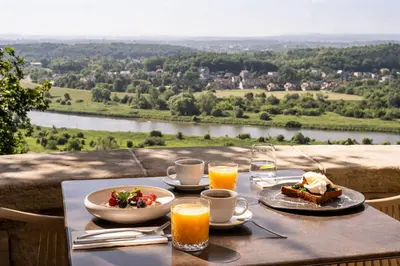 a table with food and drinks and a view of a river at Forest Hotel in Kraków