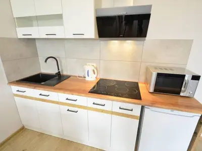 a kitchen with white cabinets and a sink and a microwave at Apartament Korazone ZATOR in Zator