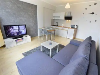 a living room with a blue couch and a kitchen at Apartament Korazone ZATOR in Zator