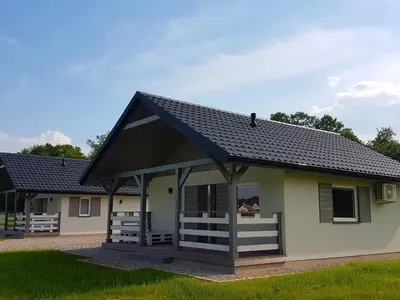a house with a pitched roof and a porch at Domki Komfort całoroczne in Zator
