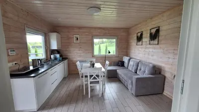 a kitchen and living room with a couch and a table at Domki Komfort całoroczne in Zator