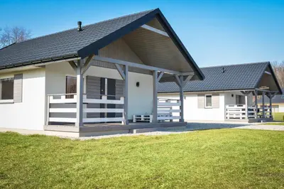 a white house with a black roof at Domki Komfort całoroczne in Zator