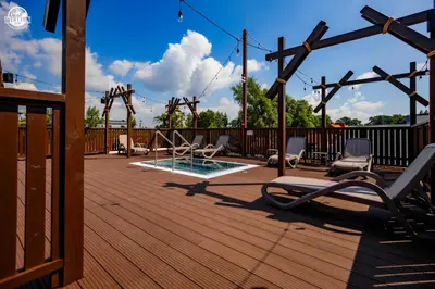 a wooden deck with a playground with chairs and a pool at Western Camp Resort in Zator
