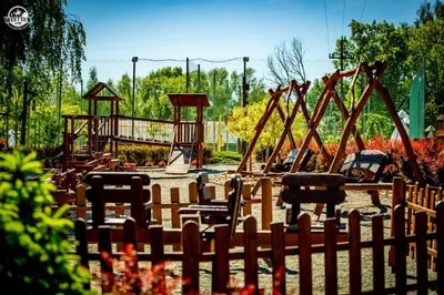 a park with a playground with a wooden fence at Western Camp Resort in Zator