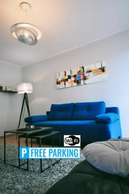 a living room with a blue couch and a table at Aquapark by JoApart - with underground garage box in Kraków