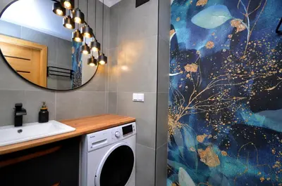 a bathroom with a sink and a washing machine at Aquapark by JoApart - with underground garage box in Kraków