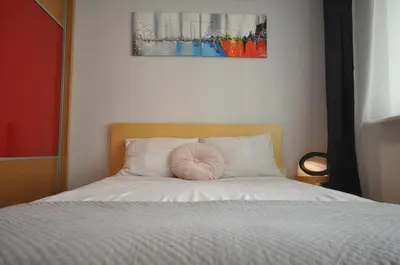 a bed with a pink pillow sitting on top of it at Aquapark by JoApart - with underground garage box in Kraków