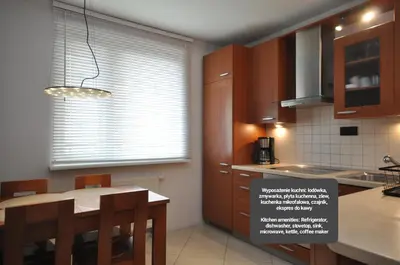 a kitchen with wooden cabinets and a table with chairs at Aquapark by JoApart - with underground garage box in Kraków