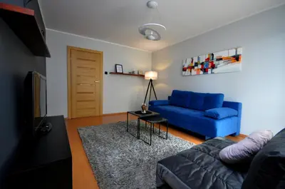 a living room with a blue couch and a table at Aquapark by JoApart - with underground garage box in Kraków