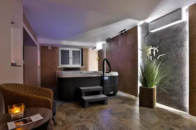 a room with a tub and a chair and a table at Hotel Wiosna in Rabka
