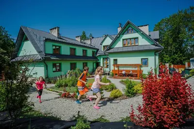 a group of children playing in front of a house at Hotel Wiosna in Rabka