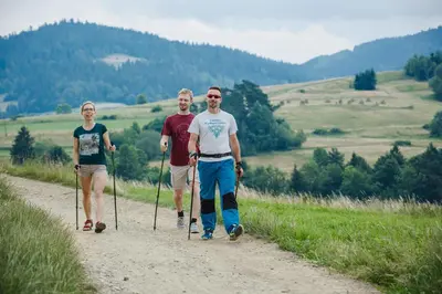 three people walking down a dirt road with poles at Hotel Wiosna in Rabka