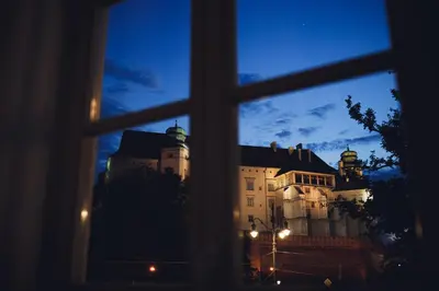 a view of a castle seen through a window at STRADOMSKA 2 APARTMENTS in Kraków