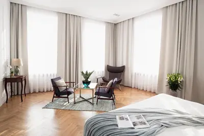 a hotel room with a bed and chairs and windows at STRADOMSKA 2 APARTMENTS in Kraków