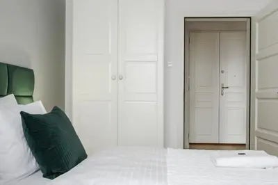 a bedroom with a white bed with a green pillow at STRADOMSKA 2 APARTMENTS in Kraków