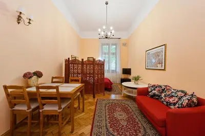 a living room with a table and a red couch at Apartamenty Pod Aniołami in Kraków