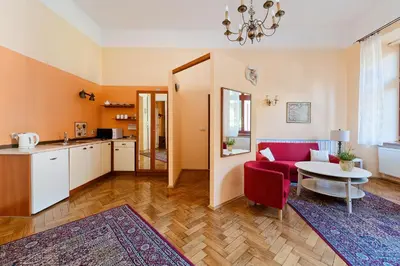 a kitchen and a living room with a red couch and a table at Apartamenty Pod Aniołami in Kraków